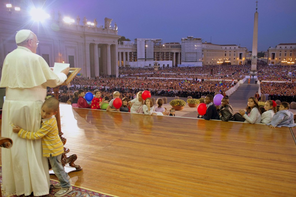 A child embraces Pope Francis as he leads a special audience with families at St. Peter Square in Vatican